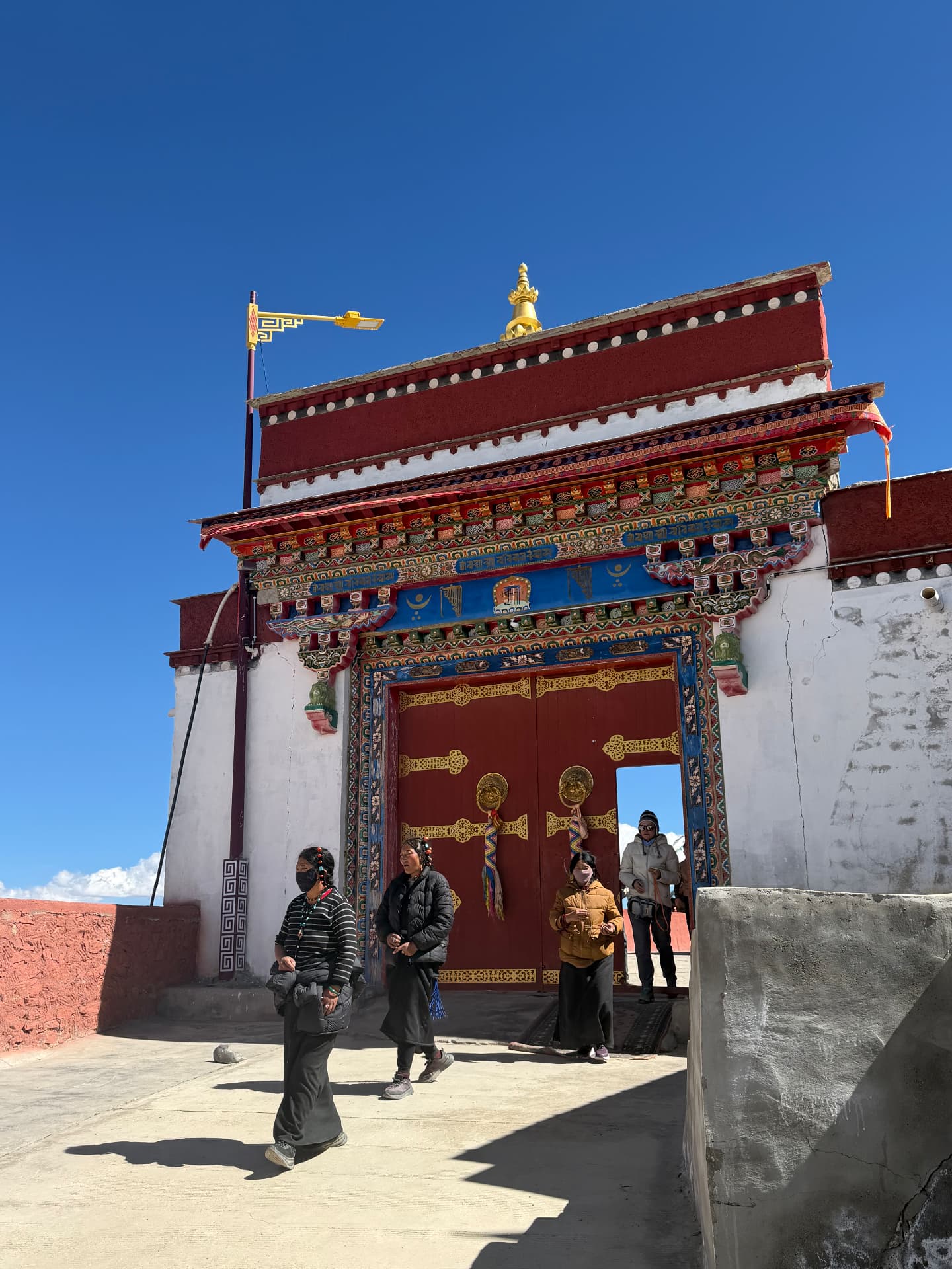 The ornately painted gate of the monastery near 1376 Homestay, pilgrims passing beneath